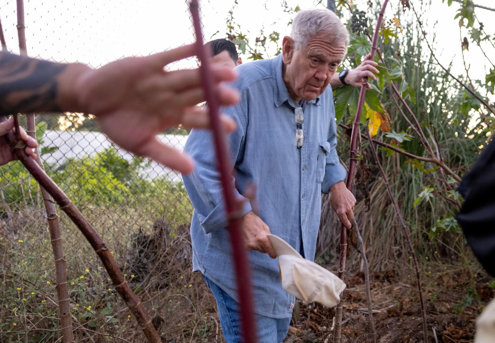 U.S. marshals clear away brush as U.S. District Judge David O. Carter walks thorough an overgrown thicket.