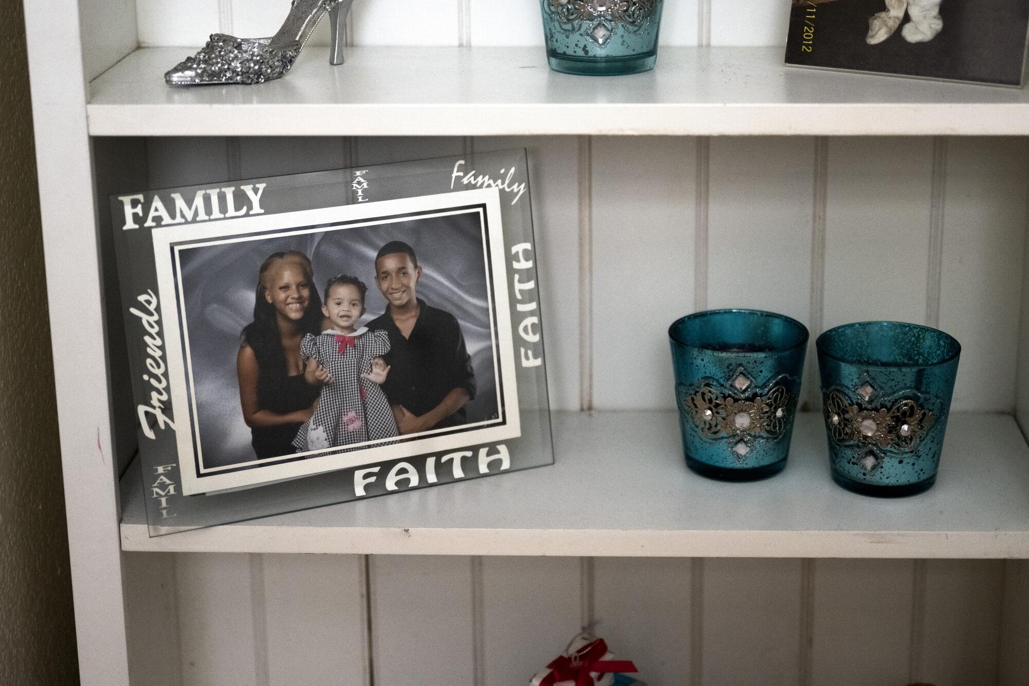 A photo of three children sits on a shelf with decorative objects.