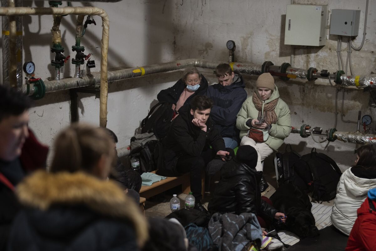 People dressed in winter clothes huddle in the corner of a basement