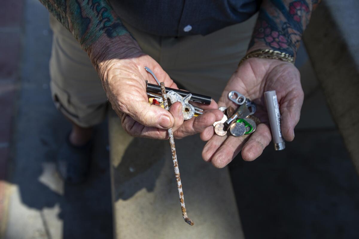 Stan Ross shows a pile of mostly worthless metal objects in his hands.