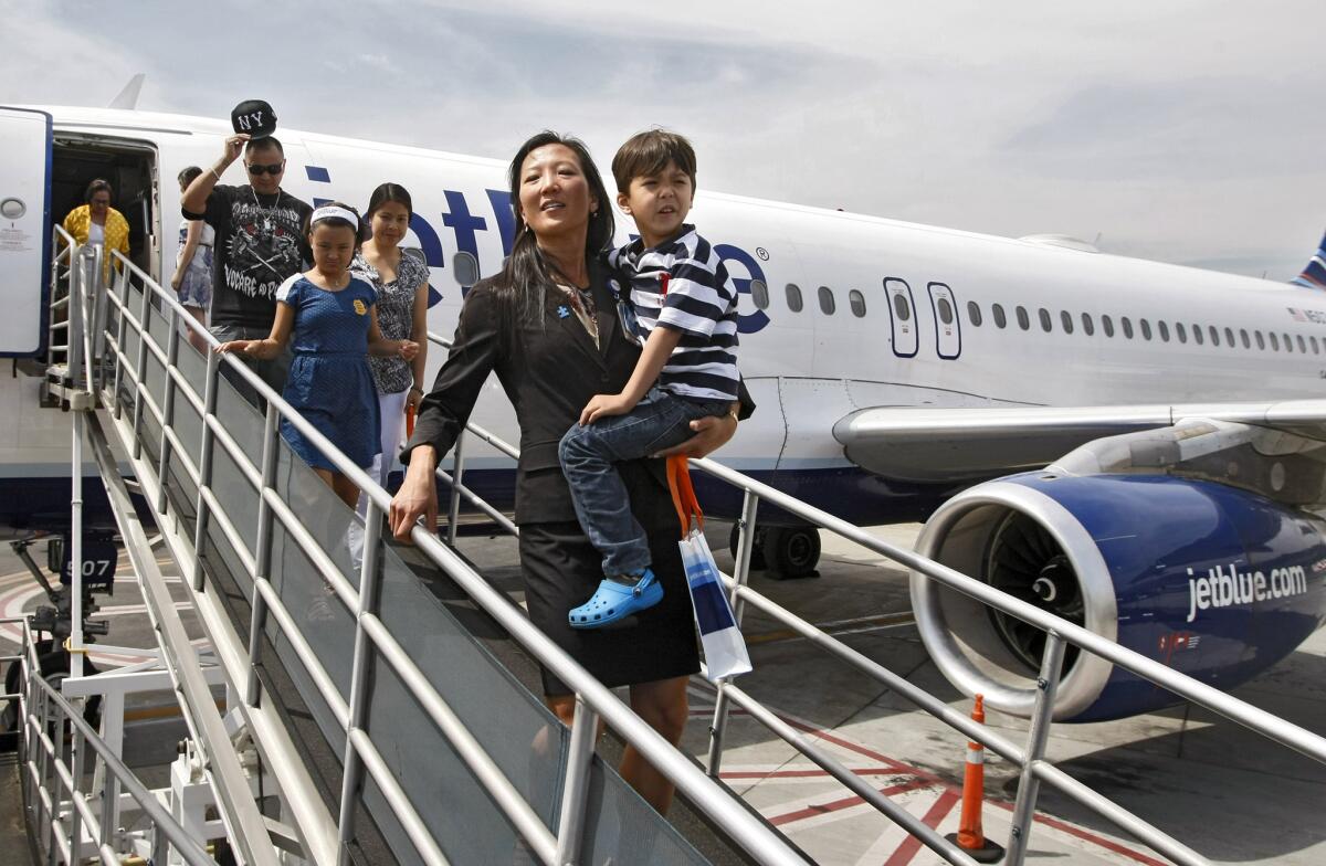 Christine Choe carries her son Lorenzo Taylor, 5, of Burbank, off the plane at the Blue Horizons for Autism event sponsored by Jet Blue Airways, Autism Speaks, and the TSA at Bob Hope Airport in Burbank on Saturday, May 3, 2014. Families affected with autism had the chance to practice the travel experience in a realistic, relaxing setting by going through the airport, checking in and boarding a plane. Choe works for Jet Blue as well.