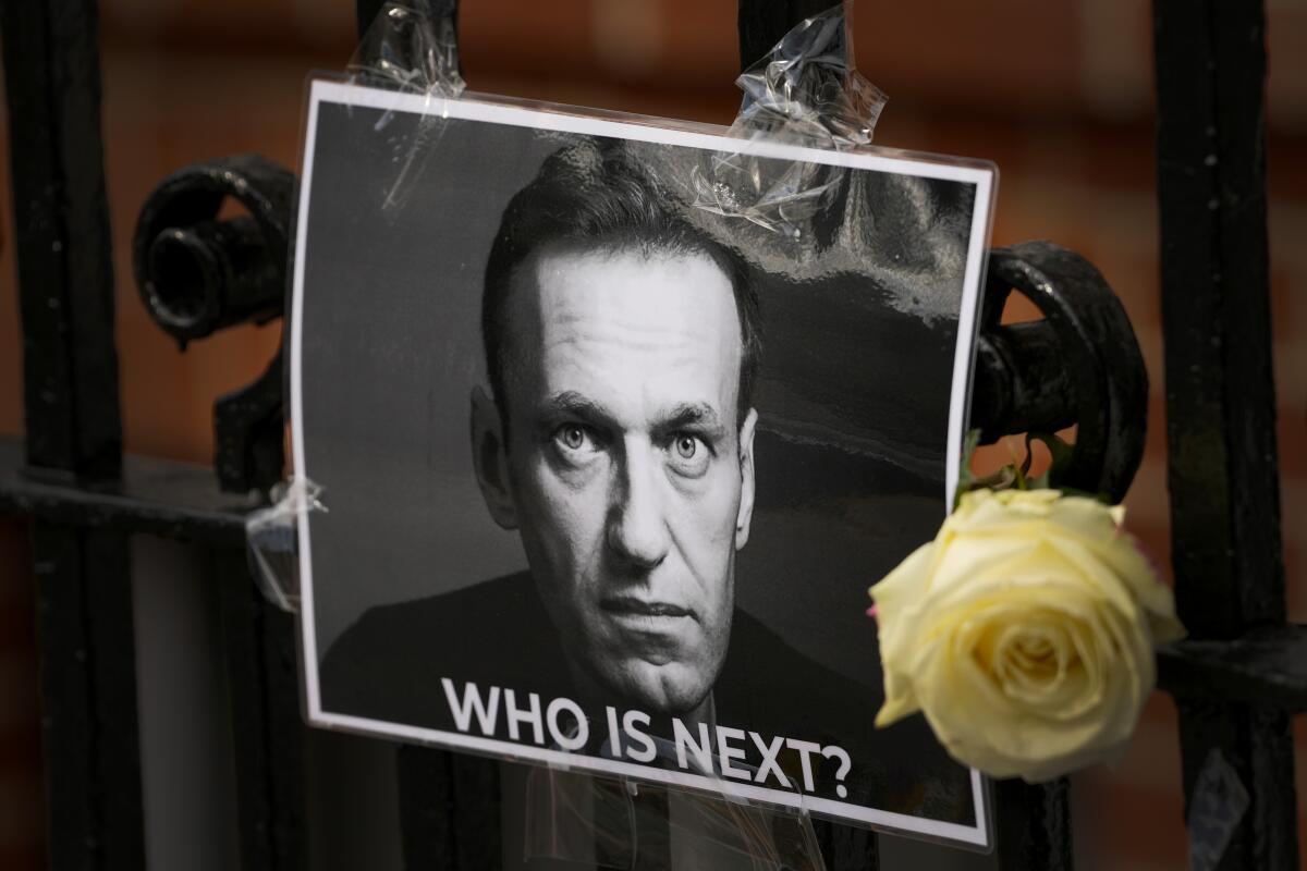 A flower and picture of Alexei Navalny with the words "Who is Next?" are left near the Russian Embassy in London.