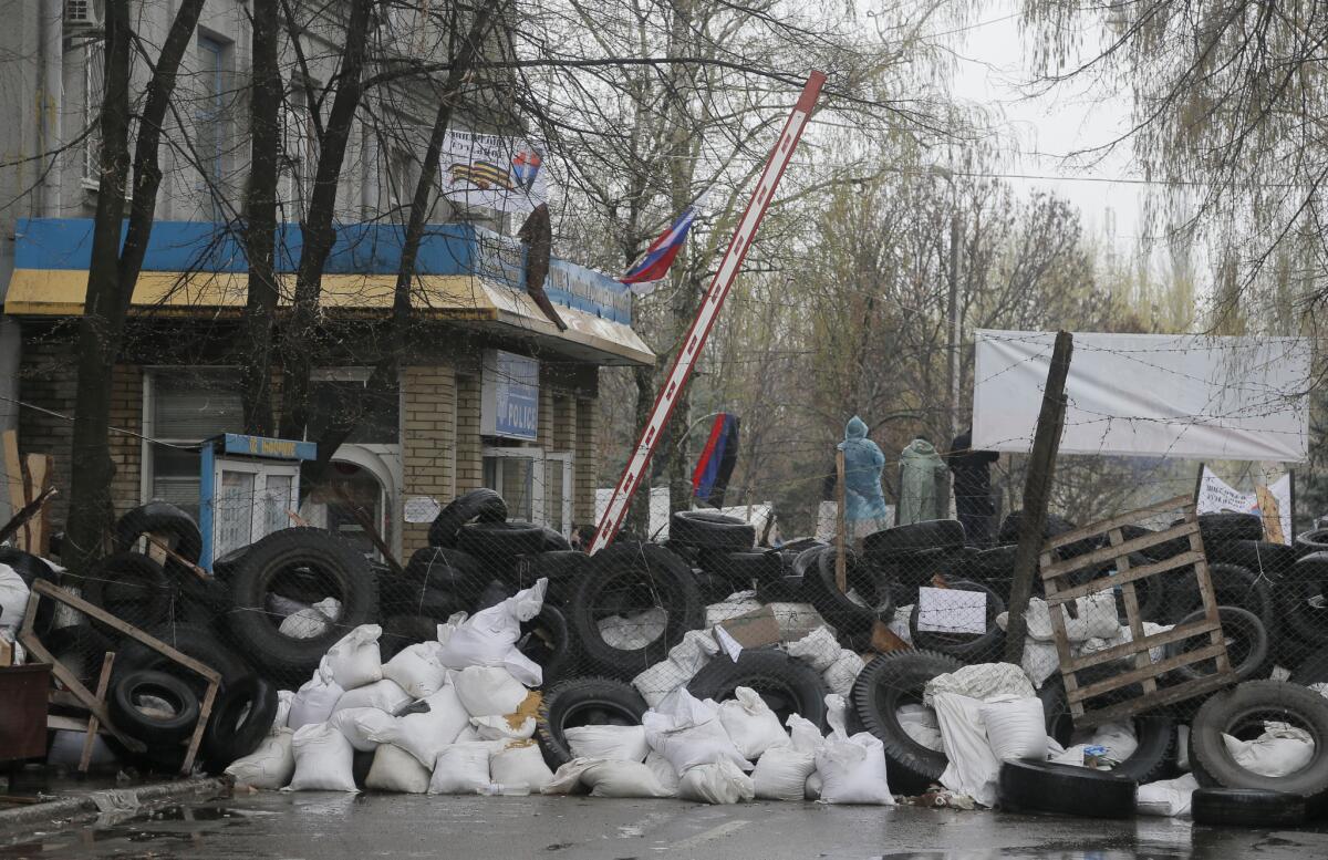 Pro-Russia gunmen stand behind a barrier of tires and trash outside a police station they seized in the eastern Ukraine town of Slavyansk.
