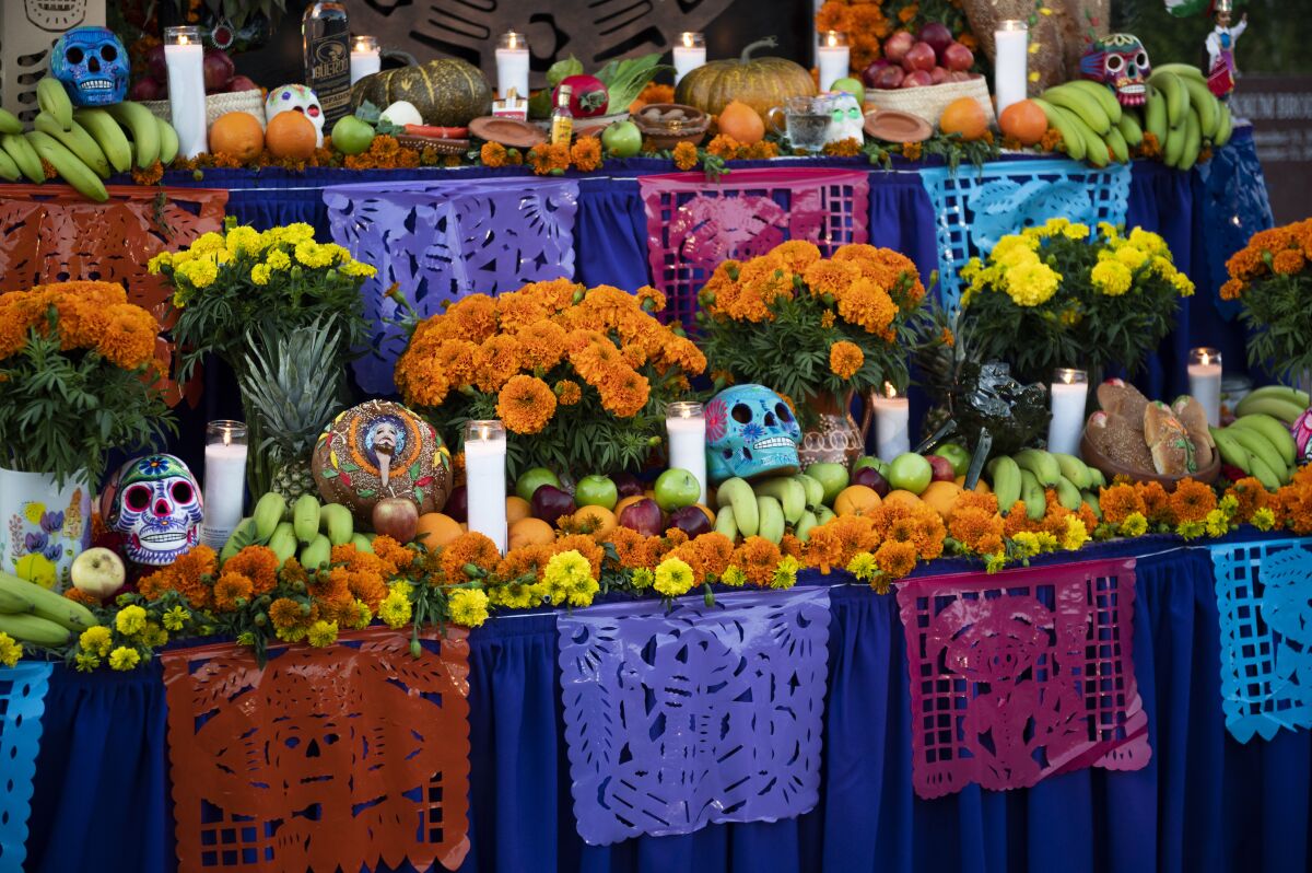 Papel picado, marigolds, fruit, painted sugar skulls and candles on an altar