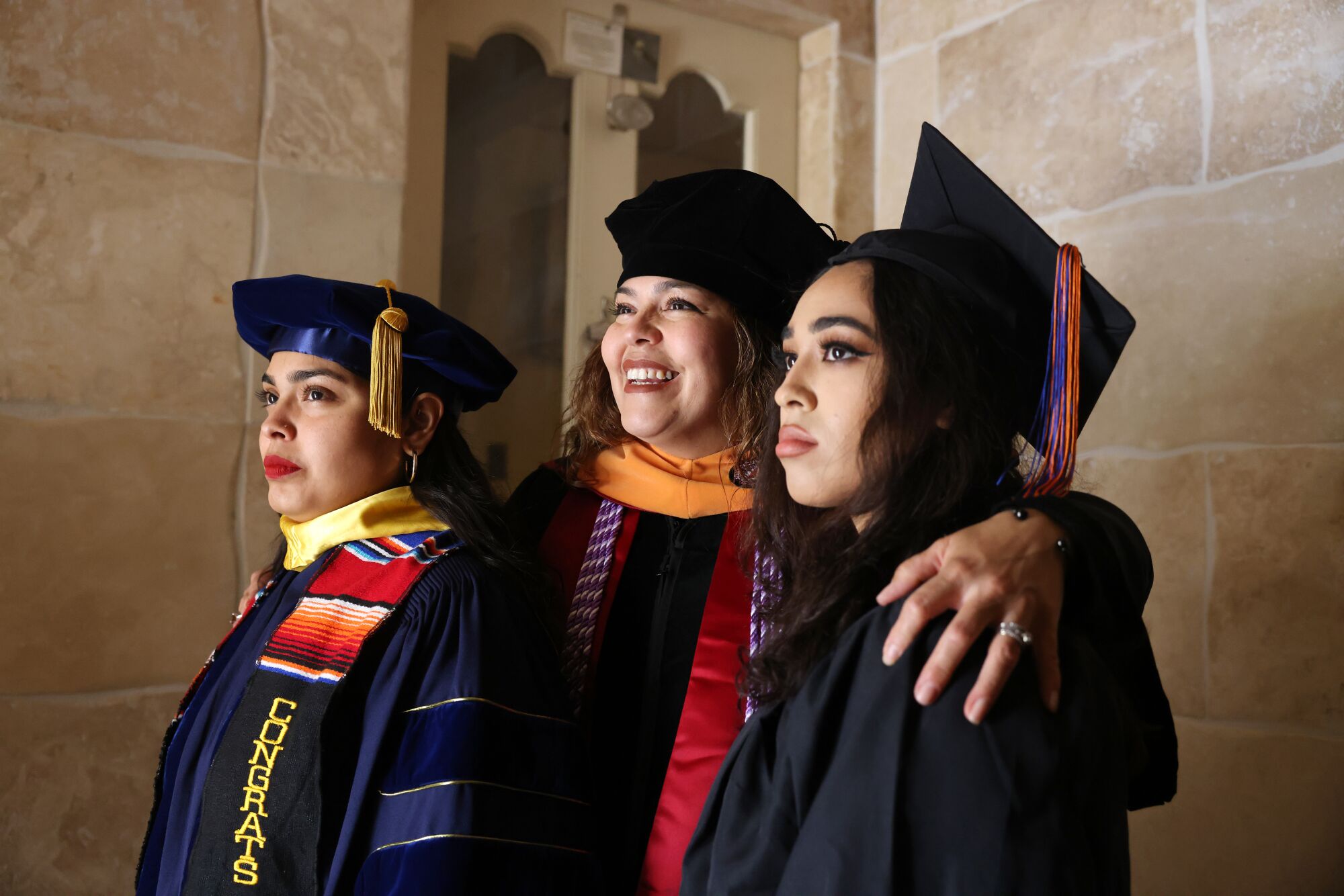 Cindy, Cecilia and Abigail Escobedo pose for photos in their caps and gowns.