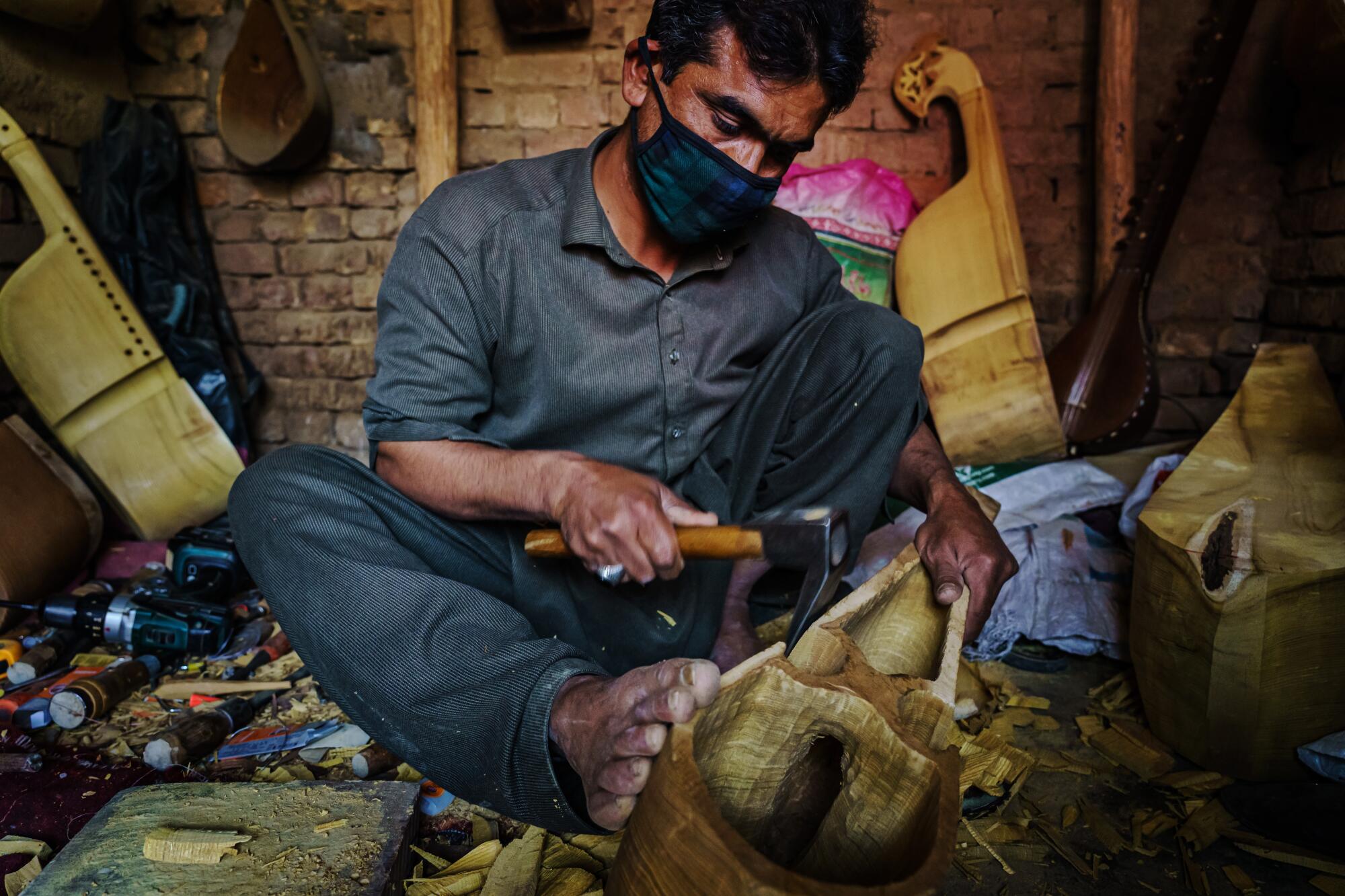 Izzatullah Neamat carves a block of wood to make a traditional Afghan rubab.
