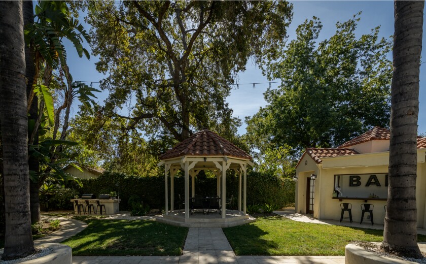 La retraite de l'amuseur comprend une cour arrière de style resort avec une piscine, un spa, un gazebo et une cabane avec un bar.'s retreat includes a resort-style backyard with a pool, spa, gazebo and cabana with a bar.