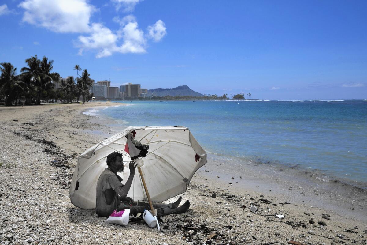 A homeless man sits on the beach at Ala Moana Beach Park in Honolulu. Hawaii now has the nation's highest rate of homeless people per capita.