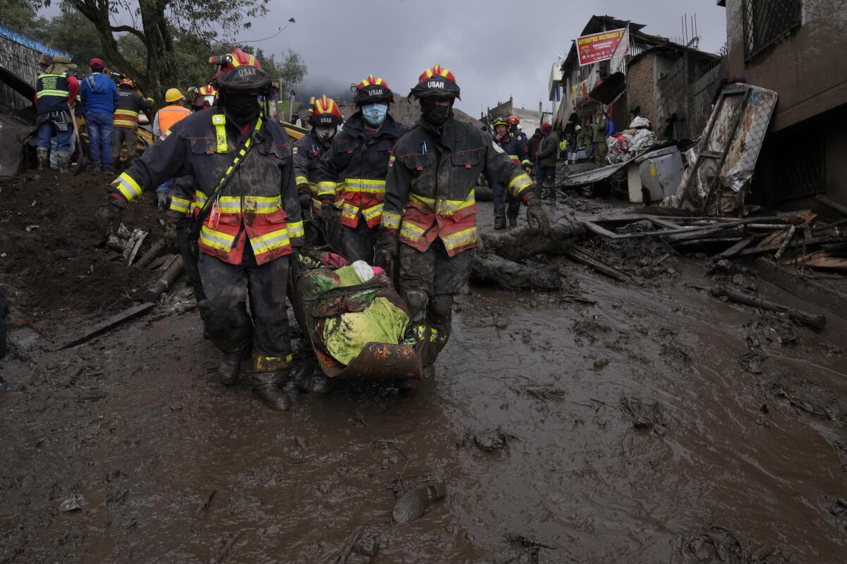 Rescue workers carry away the body of a victim of flash flooding in La Gasca area of Quito, Ecuador