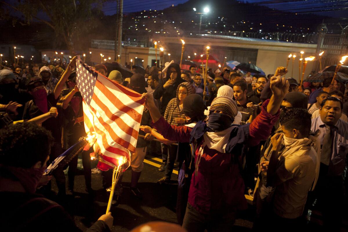 Manifestantes queman una bandera de Estados Unidfos durante una marcha para exigir la renuncia del presidente hondureño Juan Orlando Hernández frente a la embaja estadounidense en Tegucigalpa, Honduras, 12 de junio de 2015. Hernández descartó el miércoles 17 de junio de 2015 que el Congreso estadounidense rehúse desembolsar los 1.000 millones de dólares que solicitó el presidente Barack Obama para América Central a raíz de los escándalos de corrupción surgidos recientemente en su país y en Guatemala. (AP Foto/Fernando Antonio)