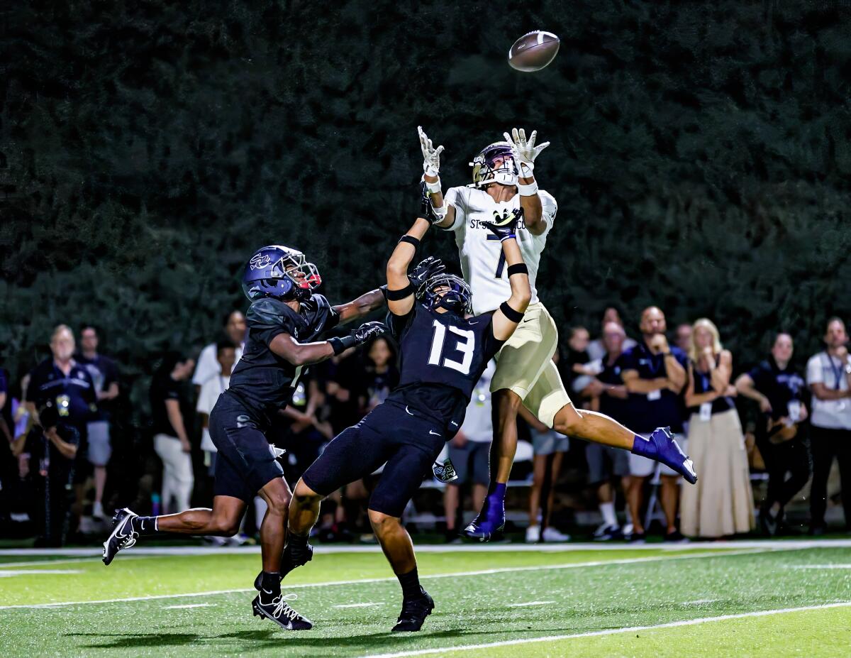 St. John Bosco's Madden Williams leaps to make catch between two Sierra Canyon defenders for 45-yard gain.