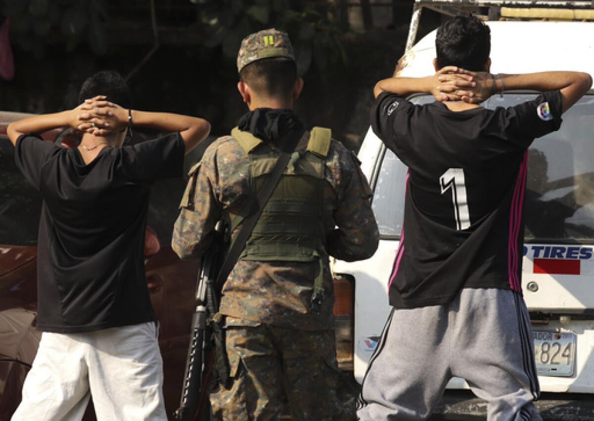 Un militar comprueba la identidad de dos jóvenes en plena calle en el barrio de La Campanera en Soyapango, 