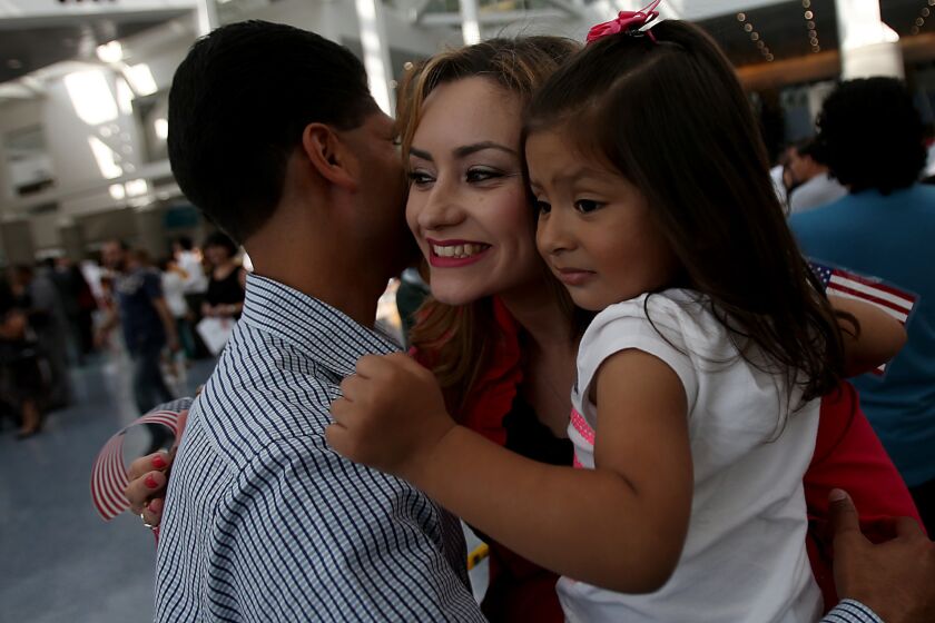 Lizbeth Lopez, a native of Mexico, gets a hug from husband Eleseo Lopez and their daughter, Damaris, 2, after getting her American citizenship at a naturalization ceremony at the Los Angeles Convention Center.
