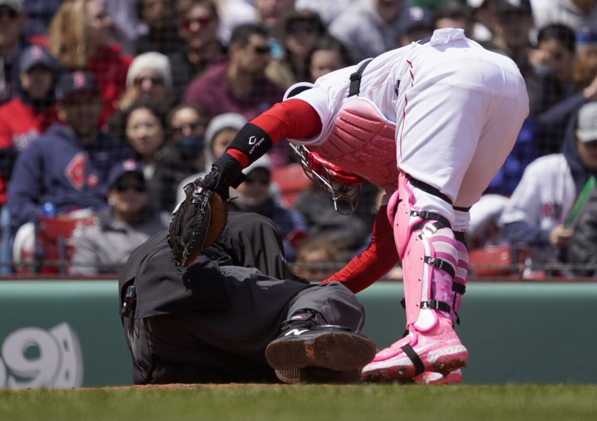 Boston Red Sox catcher Christian Vazquez checks on home plate umpire Ron Kulpa after being hit with a foul ball during the fourth inning of a baseball game between the Boston Red Sox and the Chicago White Sox at Fenway Park, Sunday, May 8, 2022, in Boston. (AP Photo/Mary Schwalm)