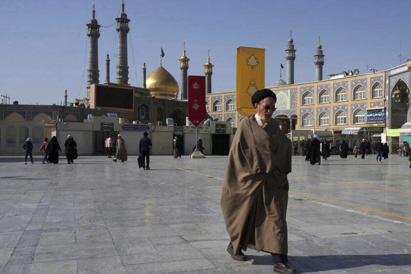 A cleric walks in front of the Fatima Masumeh Shrine at the city of Qom, some 80 miles (125 kilometers) south of the capital Tehran, Iran, Tuesday, Feb. 7, 2023. (AP Photo/Vahid Salemi)