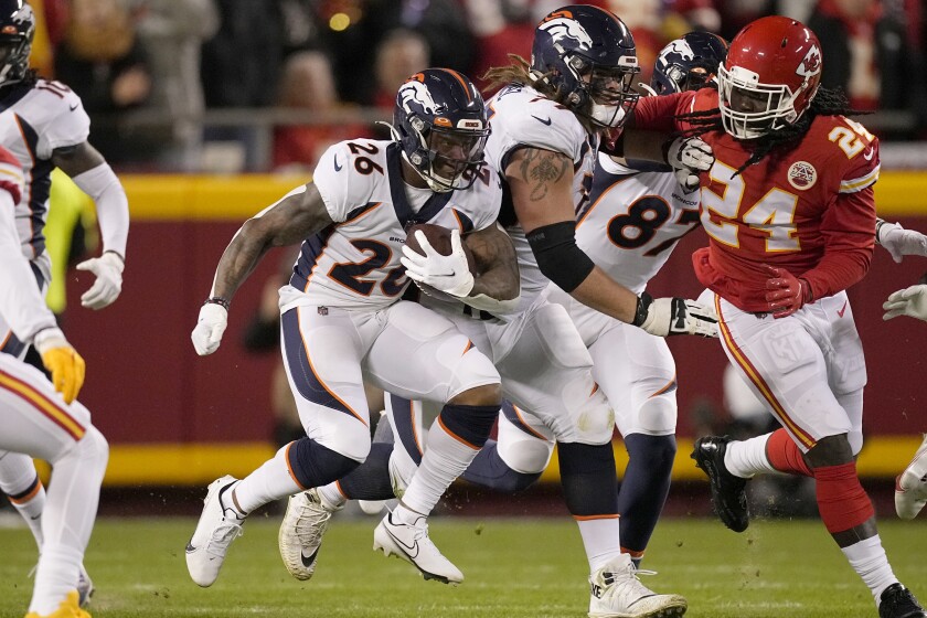 Denver Broncos running back Mike Boone (26) runs with the ball as Kansas City Chiefs linebacker Melvin Ingram III (24) defends during the first half of an NFL football game Sunday, Dec. 5, 2021, in Kansas City, Mo. (AP Photo/Charlie Riedel)