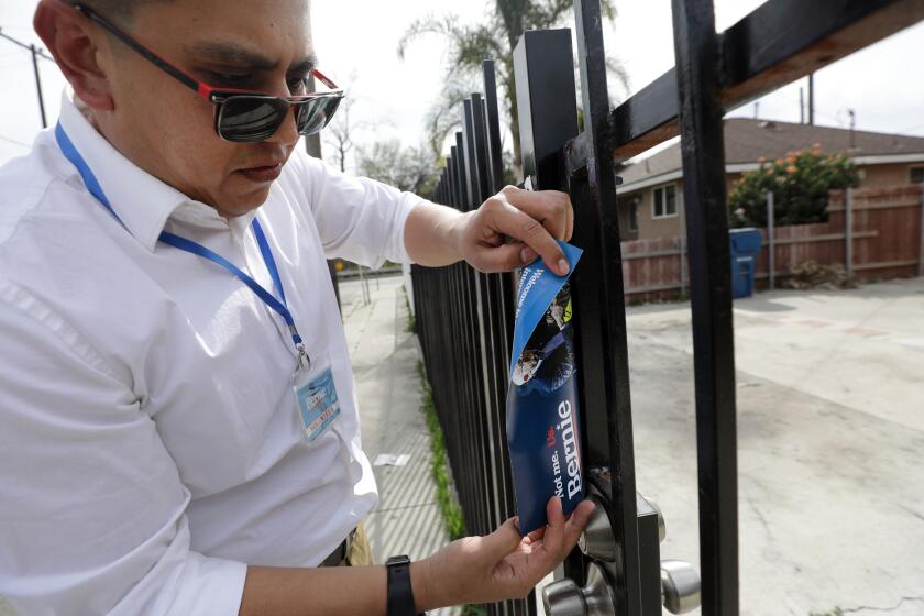 EAST LOS ANGELES, CA -- FEBRUARY 27, 2020: Ricardo Alonzo, a volunteer with the Bernie Sanders campaign, leaves a flyer at a home while canvassing an East Los Angeles neighborhood. He says he does not try to convert voters but to provide information about his candidate. (Myung J. Chun / Los Angeles Times)