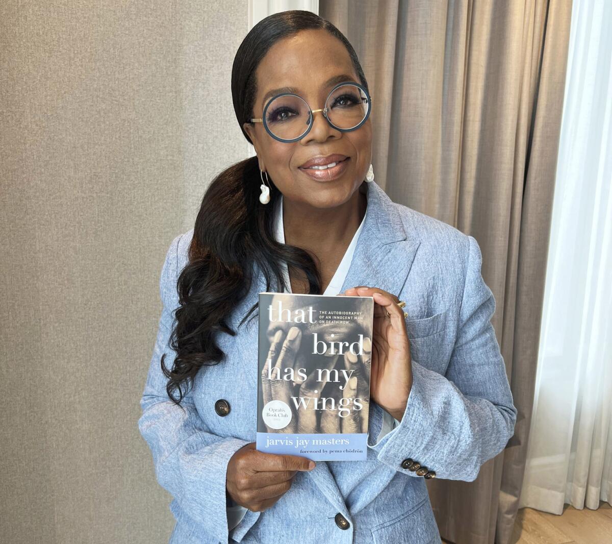 Oprah Winfrey holds up her latest book club selection, "That Bird Has My Wings,"