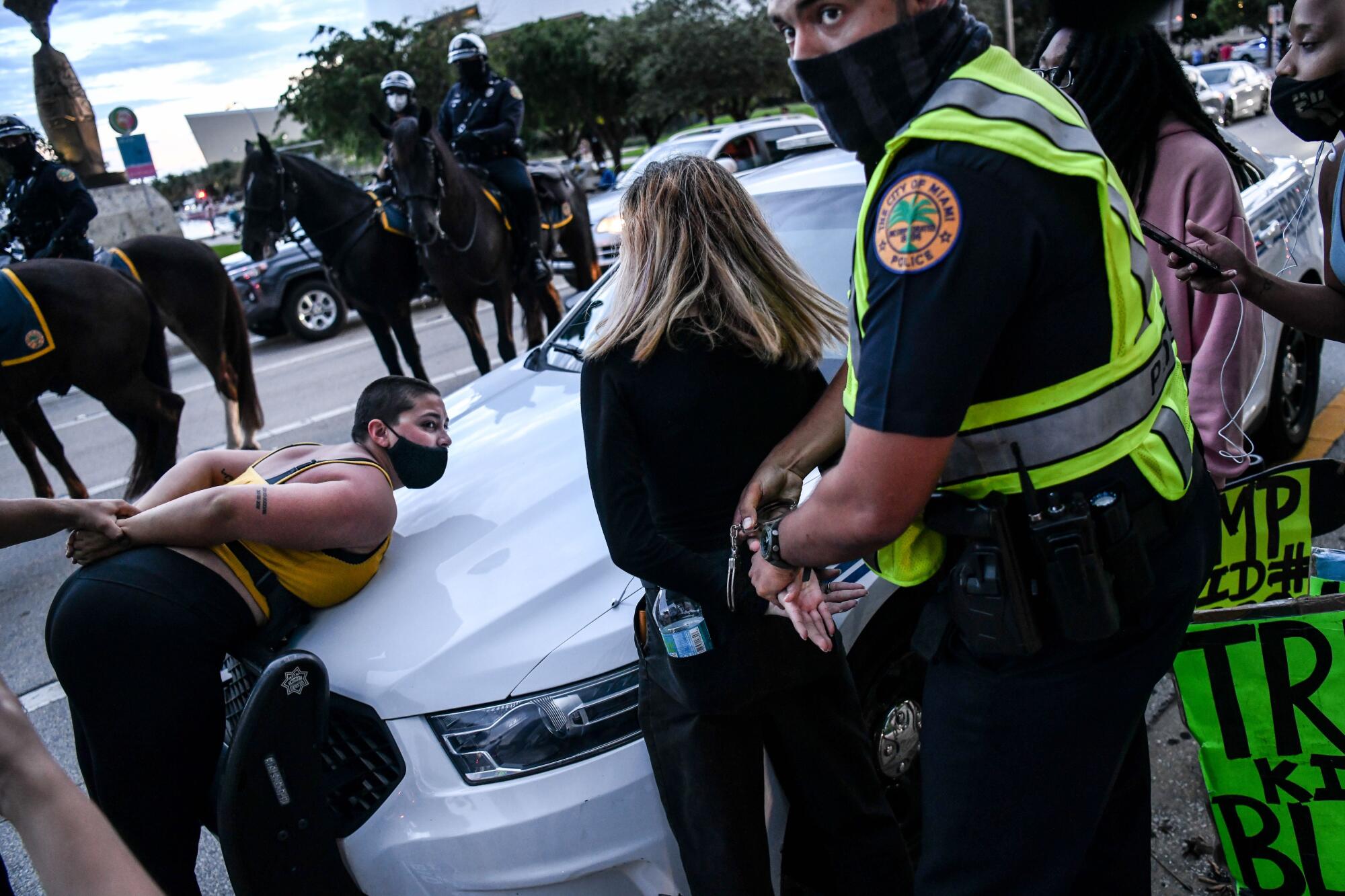 Police arrest protesters over the hood of a police cruiser