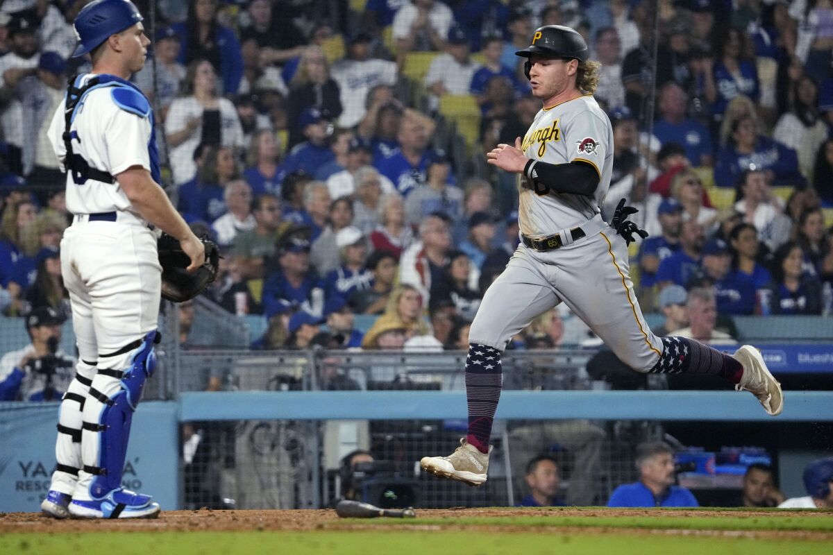 Pirates outfielder Jack Suwinski scores on a single by Jared Triolo as Dodgers catcher Will Smith stands.