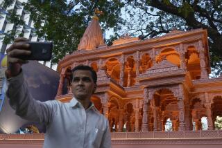 A person takes selfie in front of a replica of the Lord Ram temple in Ayodhya, which is on display outside India's ruling Bharatiya Janata Party office, in Mumbai, India, Tuesday, Jan. 16, 2024. (AP Photo/Rafiq Maqbool)