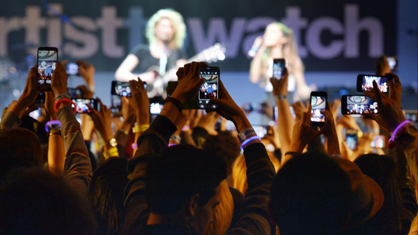 Fans using smartphones record a performance by Tori Kelly, left, and Ariana Grande at the House Blues in January. Grande connects with fans using chat app Line.