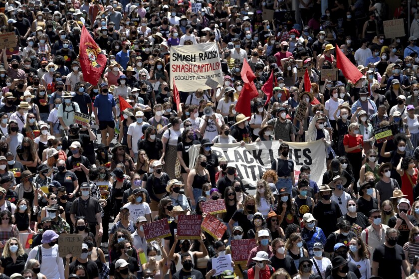 Protesters hold placards as they march during an Invasion Day rally in Sydney, Wednesday, Jan. 26. 2022. Australians celebrated and protested the anniversary of British colonization of their country on a day that is officially known as Australia Day but is considered by Indigenous activists Invasion Day. (Bianca De Marchi/AAP Image via AP)