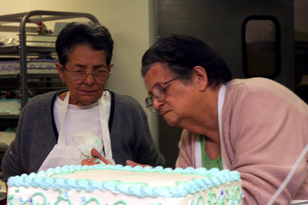 In a photo from 2001, Rosa Porto decorates a cake as Urvicia Garcia watches. Porto, who began selling cakes from her home in Cuba over 50 years ago, died Friday at age 89.