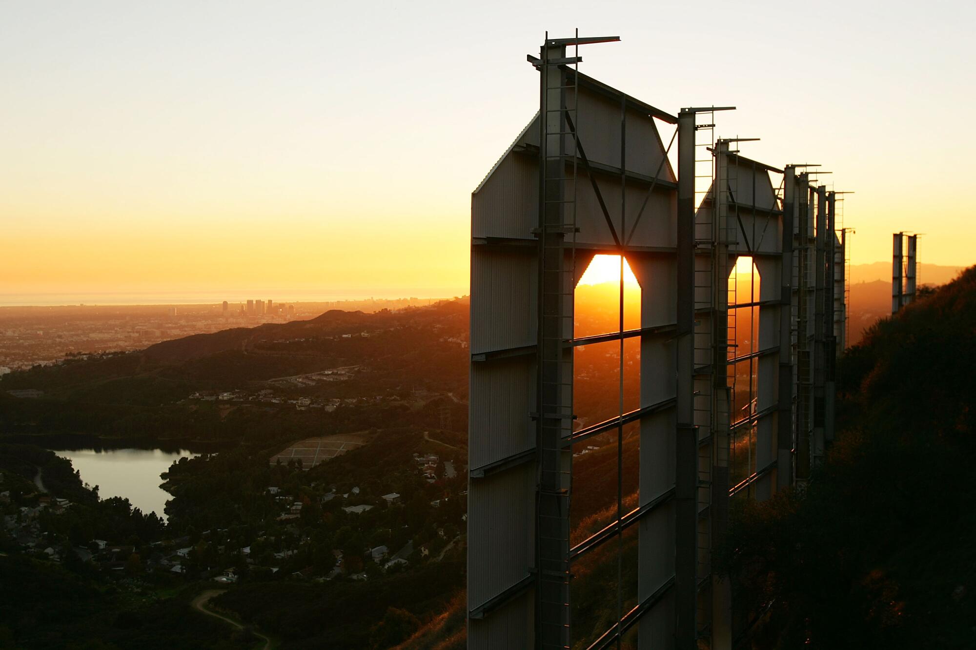 A view behind the two O's in the Hollywood sign as the sun sets in the distance