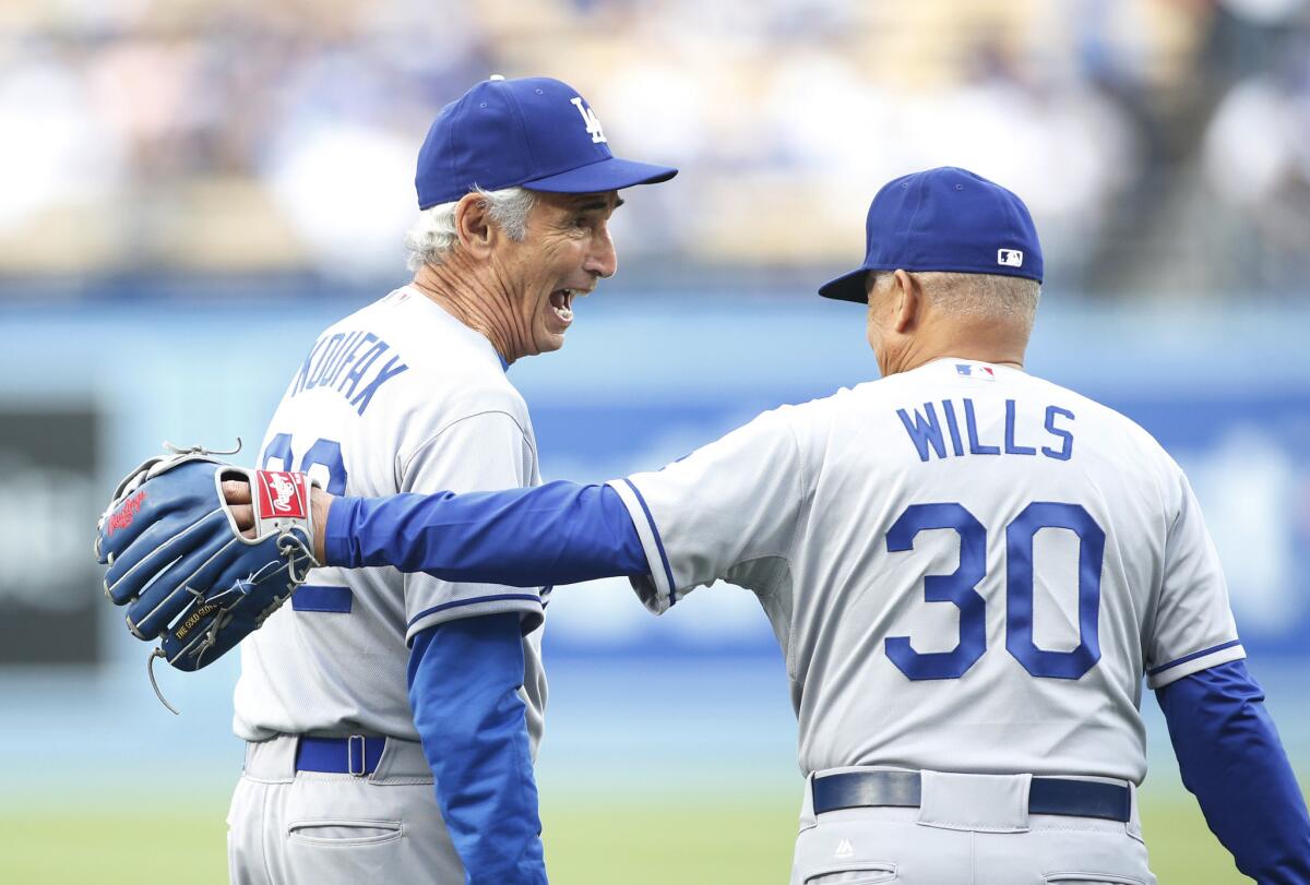Sandy Koufax, left, shares a laugh with Maury Wills before the old-timers’ game that saluted the 50th anniversary of the Dodgers’ 1965 World Series winners before Saturday's game against Colorado.