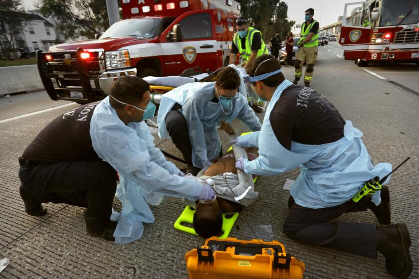 Houston, Texas-Nov. 23, 2020-Houston Fire Capt. Daniel Soto, 35, second from left, supervises as firefighters treat a man struck by a driver while crossing a highway Sunday. Soto said he feels a responsibility to continue CPR even in the most hopeless cases during the pandemic. "You'll never get in trouble for giving someone a chance," he said. (Carolyn Cole / Los Angeles Times)