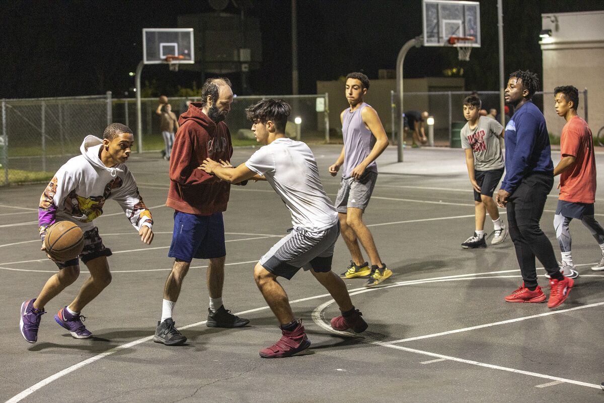 People play basketball without protective masks on at Reseda Park in Reseda.