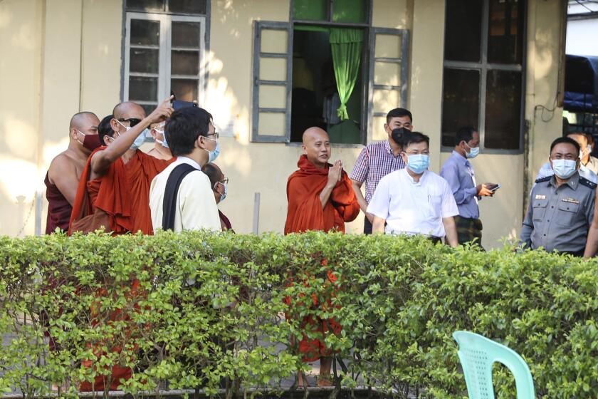 Buddhist monk Wirathu, center, gestures to his followers at a police station in Yangon, Myanmar, Monday Nov. 2, 2020. Wirathu, a nationalist Buddhist monk in Myanmar noted for his inflammatory rhetoric, has surrendered to police, who have been seeking his arrest for over a year for insulting comments he made about the country’s leader, State Counsellor Aung San Suu Kyi. (AP Photo/Thein Zaw)