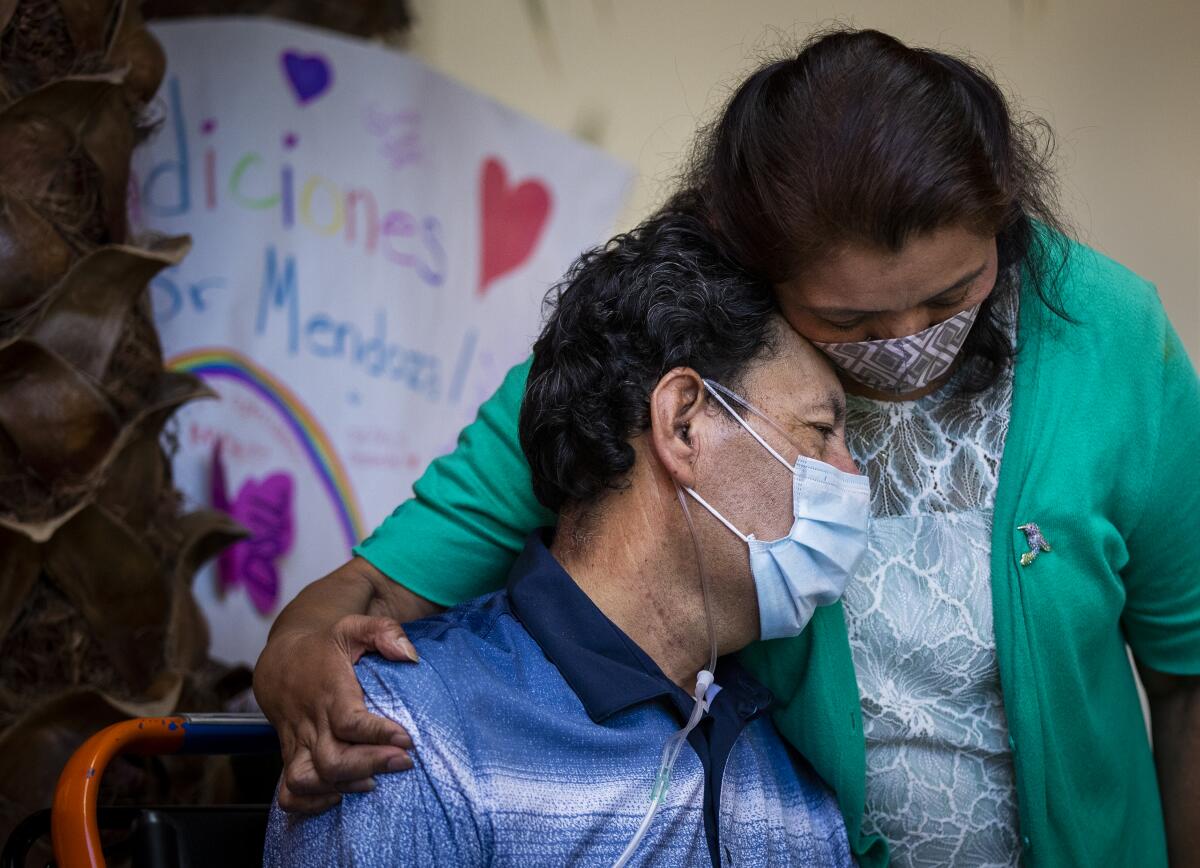 Armando Mendoza, 53, of Anaheim, who spent 45 days at St. Joseph Hospital battling COVID-19, hugs his wife Lilia after he was released Tuesday.
