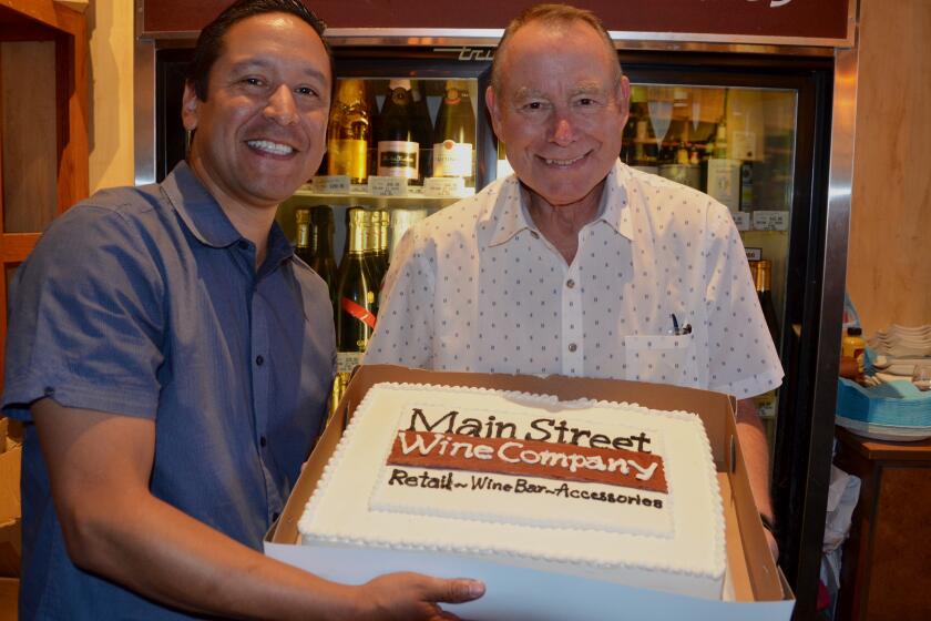 From left, Oscar Carrillo and Dann Bean, co-owners of the Main Street Winery in Huntington Beach celebrated the tenth anniversary Sunday with a custom decorated ice cream cake.
