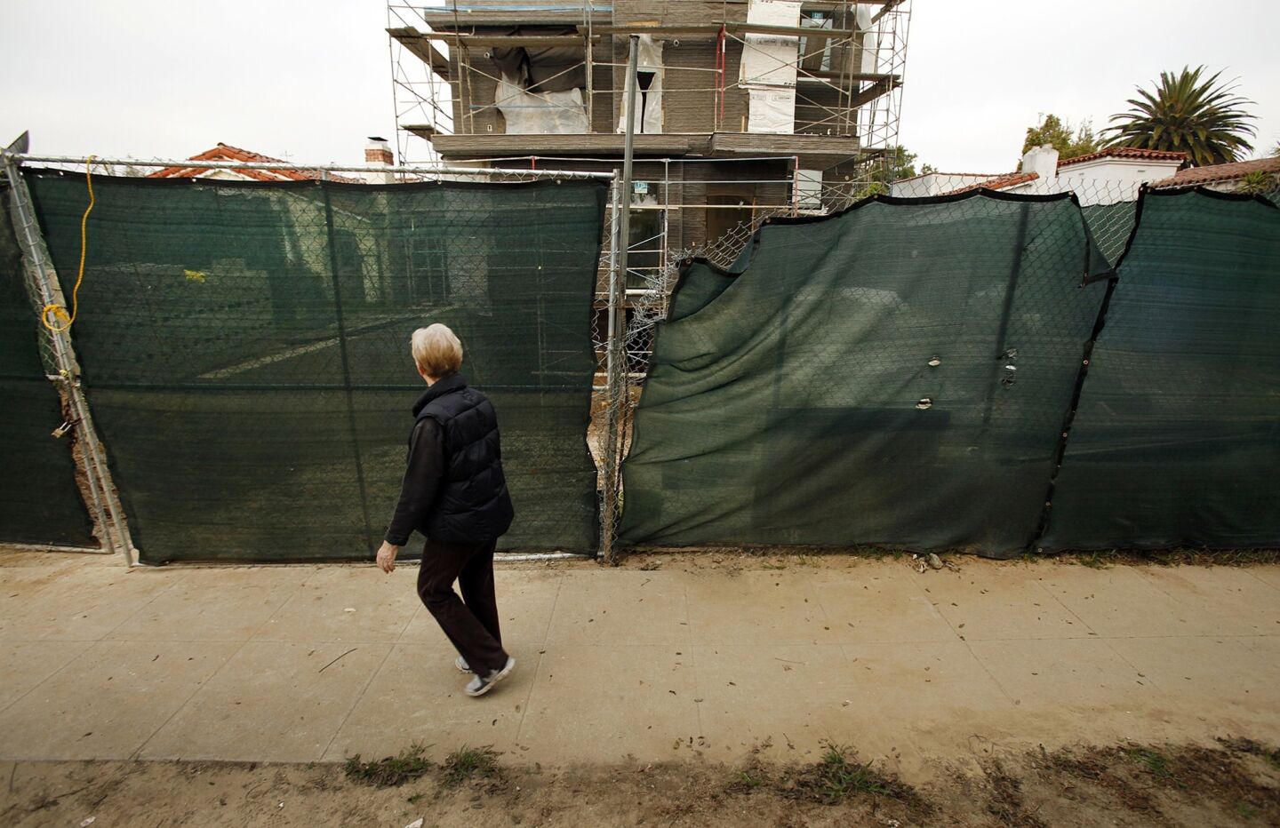 Bea Samples, who lives a few doors away, walks past a home under construction in Faircrest Heights. Neighbors believe several homes under construction in the area demonstrate examples of "mansionization" and are trying to bring attention to them.