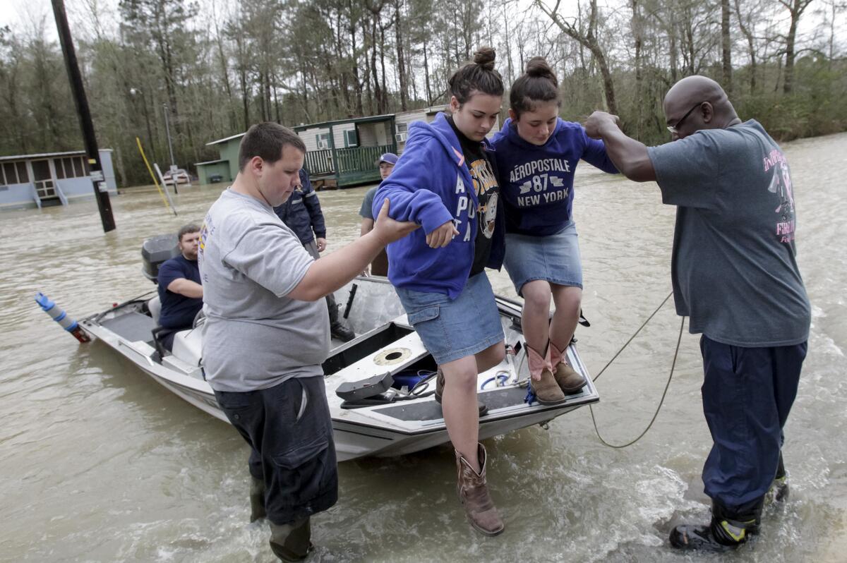 Firefighters help Briar Childress, second from left, and Jasmine Sutherland after the sisters were evacuated from their home on Highway 40 in Independence, La.