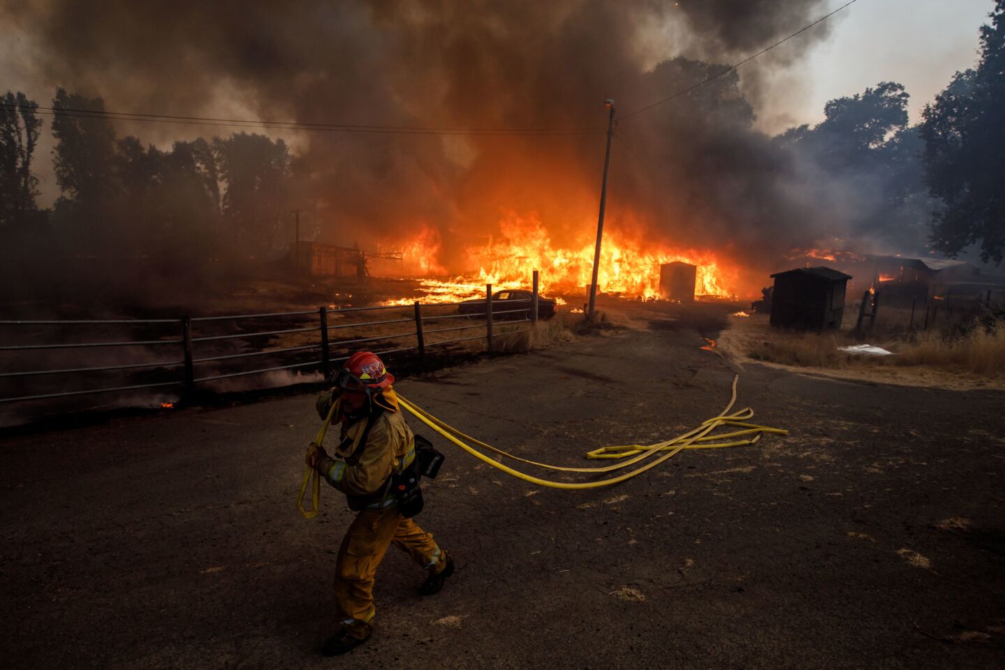 A West Covina firefighter works as a barn in the background is destroyed by the Mendocino complex fires near Lakeport, Calif., on July 31.