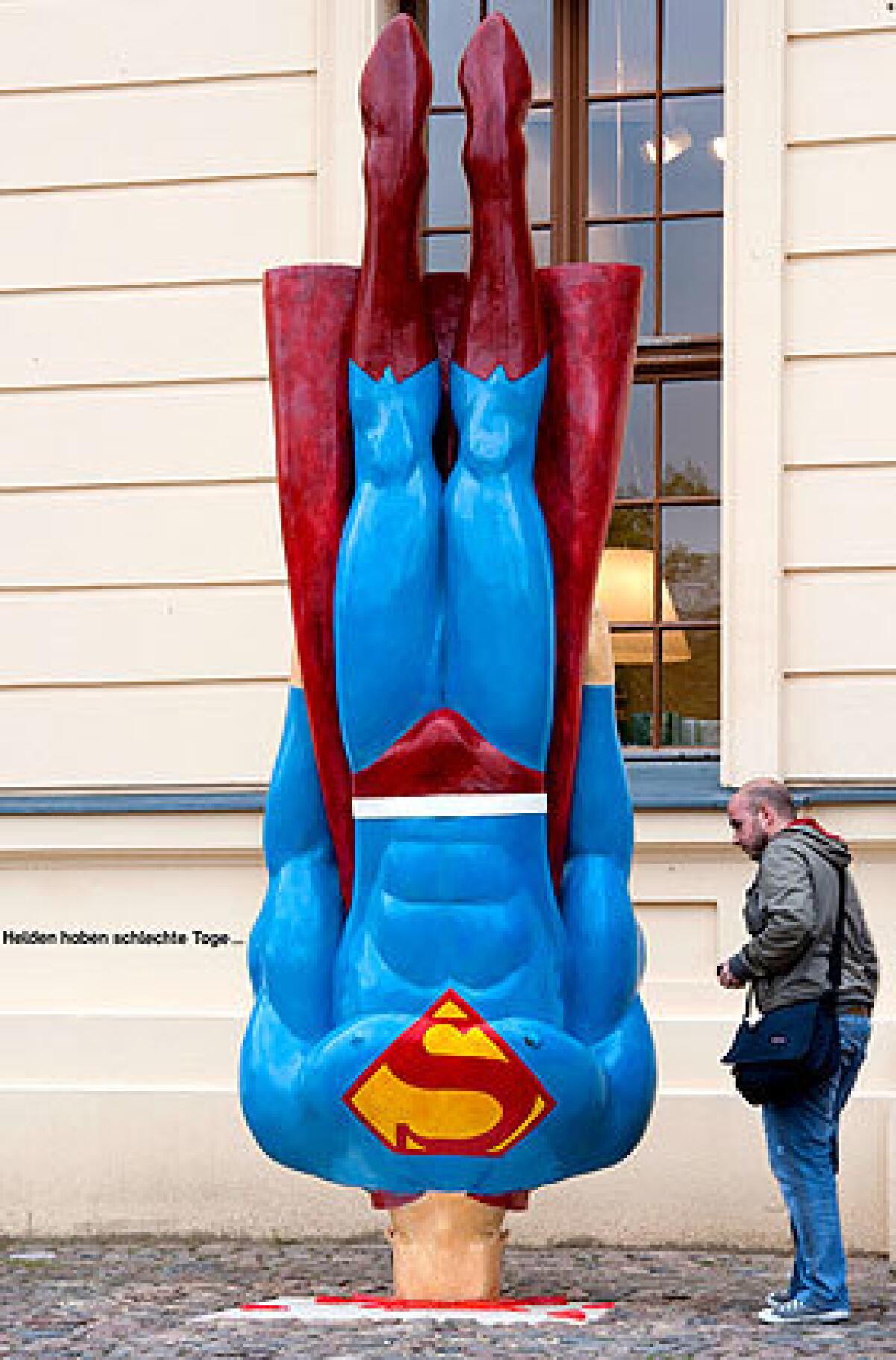 A man looks at a Superman sculpture by German artist Marcus Wittmers in front of the Jewish Museum. The sculpture called "Also Heroes Have Bad Days" is part of the exhibition "Heroes, Freaks and Superrabbis: The Jewish Dimension of the Comic."