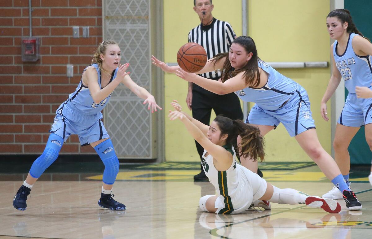Edison's Adelina Fredrick dives for a loose ball as Corona del Mar's Dorothy Schwenck, left, and Makena Tomlinson try to go for the steal during a Surf League game on Thursday.