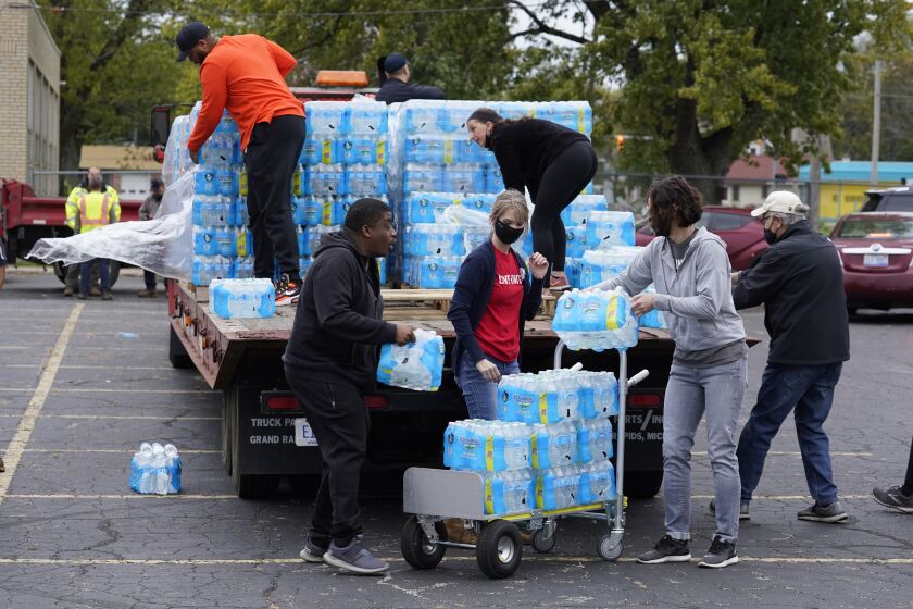 Volunteers prepare bottled water to be distributed to residents at the local high school parking lot Thursday, Oct. 21, 2021, in Benton Harbor, Mich. The water system in Benton Harbor has tested for elevated levels of lead for three consecutive years. In response, residents have been told to drink and cook with bottled water and the state has promised to spend millions replacing lead service lines. (AP Photo/Charles Rex Arbogast)
