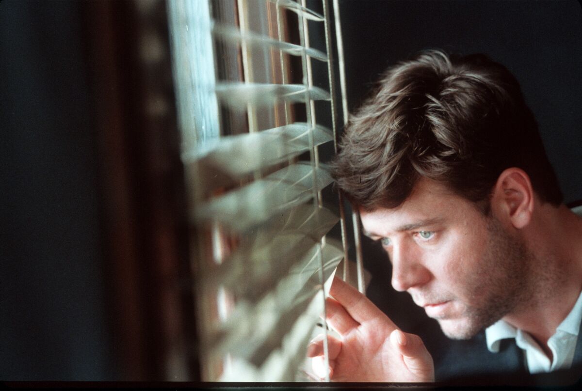 Russell Crowe peers out venetian blinds in “A Beautiful Mind” (2001).