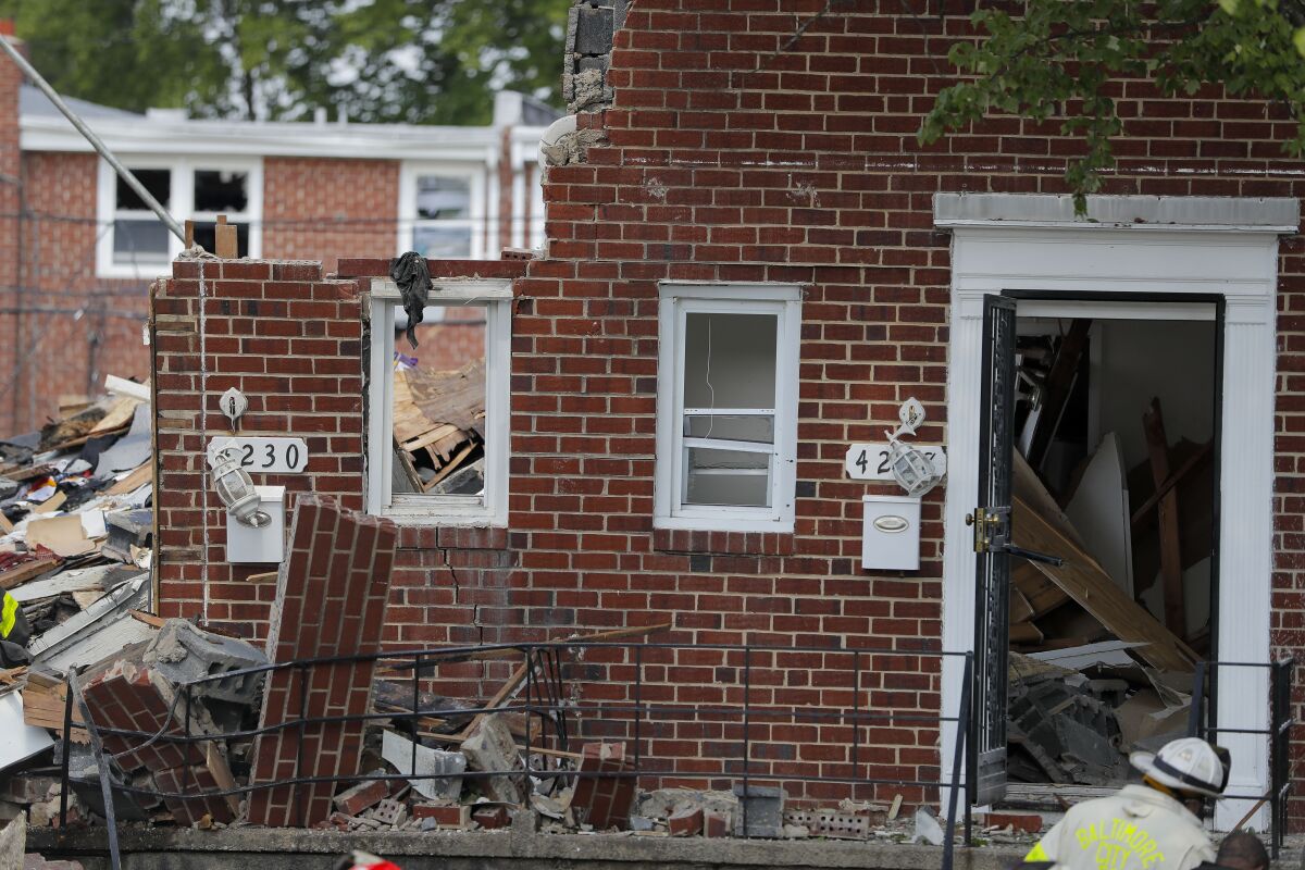 A firefighter walks near the debris in the aftermath of an explosion in Baltimore on Monday, Aug. 10, 2020. Baltimore firefighters say an explosion has leveled several homes in the city. (AP Photo/Julio Cortez)