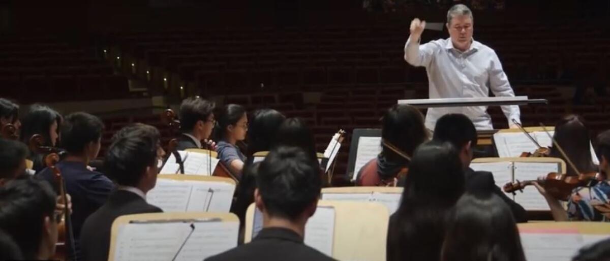 A conductor stands in front of music students in Irvine.
