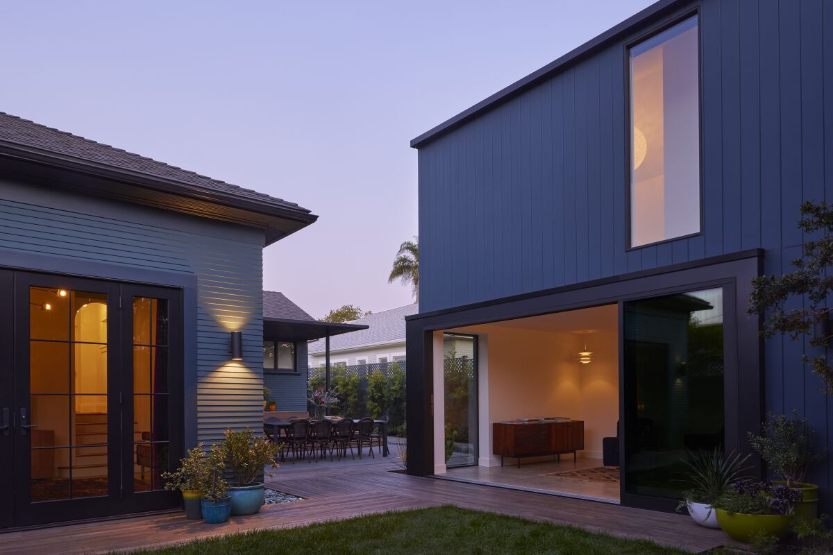 A blue 700-square-foot, two-story ADU next to a Craftsman bungalow