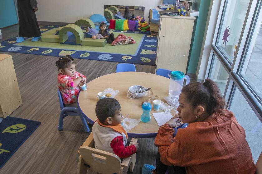 Site supervisor Cecilia Petty , lower right, attended to Infant to three-year old charges at the Children of the Rainbow Childcare Services in Barrio Logan on Friday, March 20, 2020.