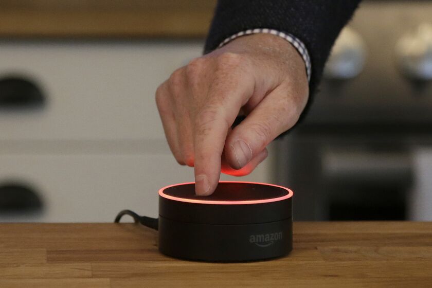 FILE - In this March 2, 2016, file photo, David Limp, Amazon Senior Vice President of Devices, pushes down on an Echo Dot in San Francisco. Voice assistants such as Google Home, Appleâs Siri and Amazon Alexa have always been susceptible to accidental hijack. In January 2017, a woman's 6-year old daughter ordered a dollhouse and sugar cookies simply by asking Alexa for them through an Echo Dot. Since these devices are still new, they're still having growing pains. But the next generation of voice assistants may come with better security, including individual voice recognition and even image recognition. (AP Photo/Jeff Chiu, File)