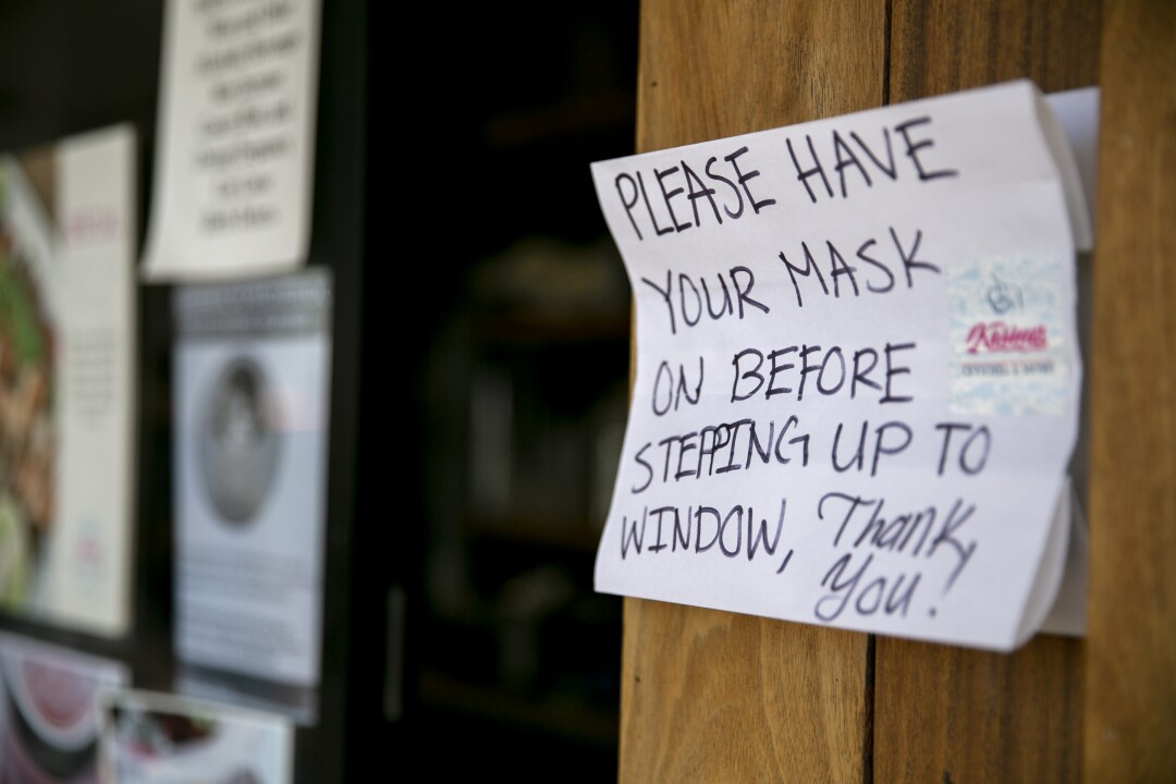 A sign asks patrons to don a mask at a restaurant