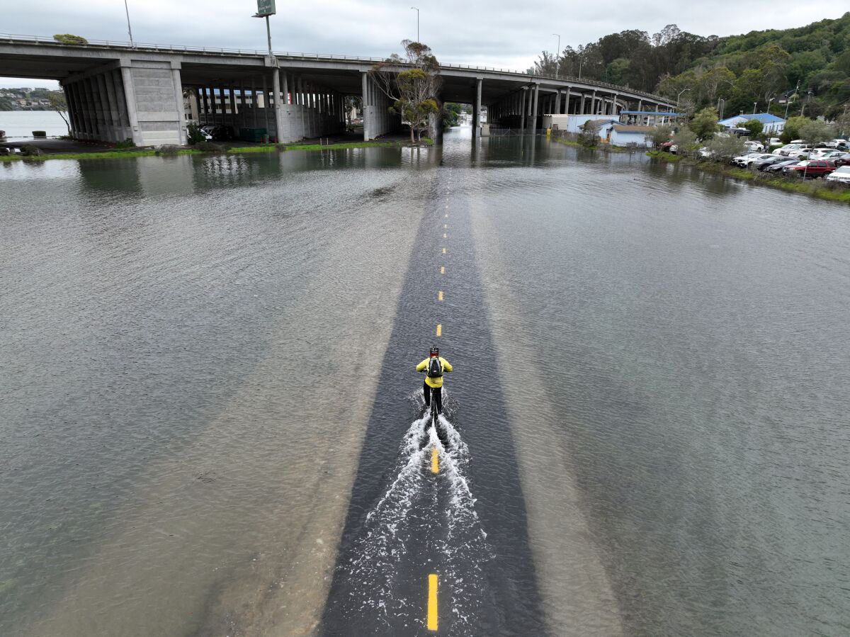 An aerial picture shows a cyclist riding through a flooded bike path in Mill Valley during a king tide in 2022.