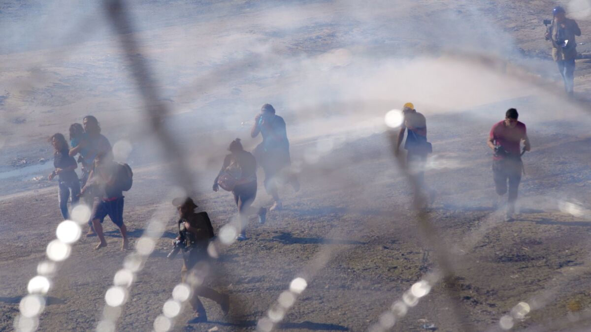 In this Nov. 25, 2018 file photo, migrants run from tear gas launched by U.S. agents, amid members of the press covering the Mexico-U.S. border, after a group of migrants got past Mexican police at the Chaparral crossing in Tijuana, Mexico.